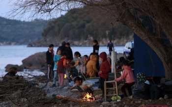 vluchtelingen zitten rond kampvuur